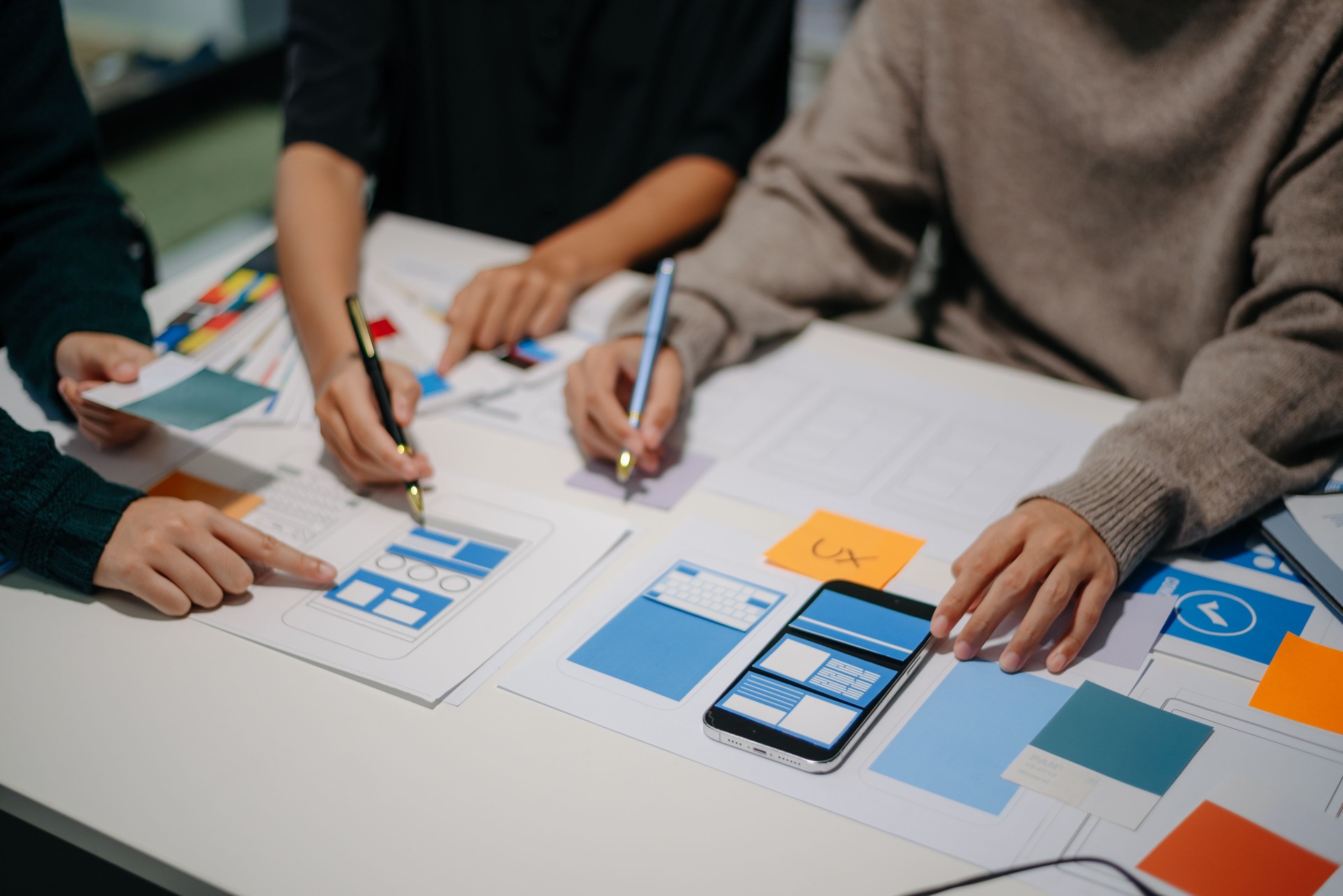 Close up view of UI developer team brainstorming on their project with laptop, smartphone and digital tablet.